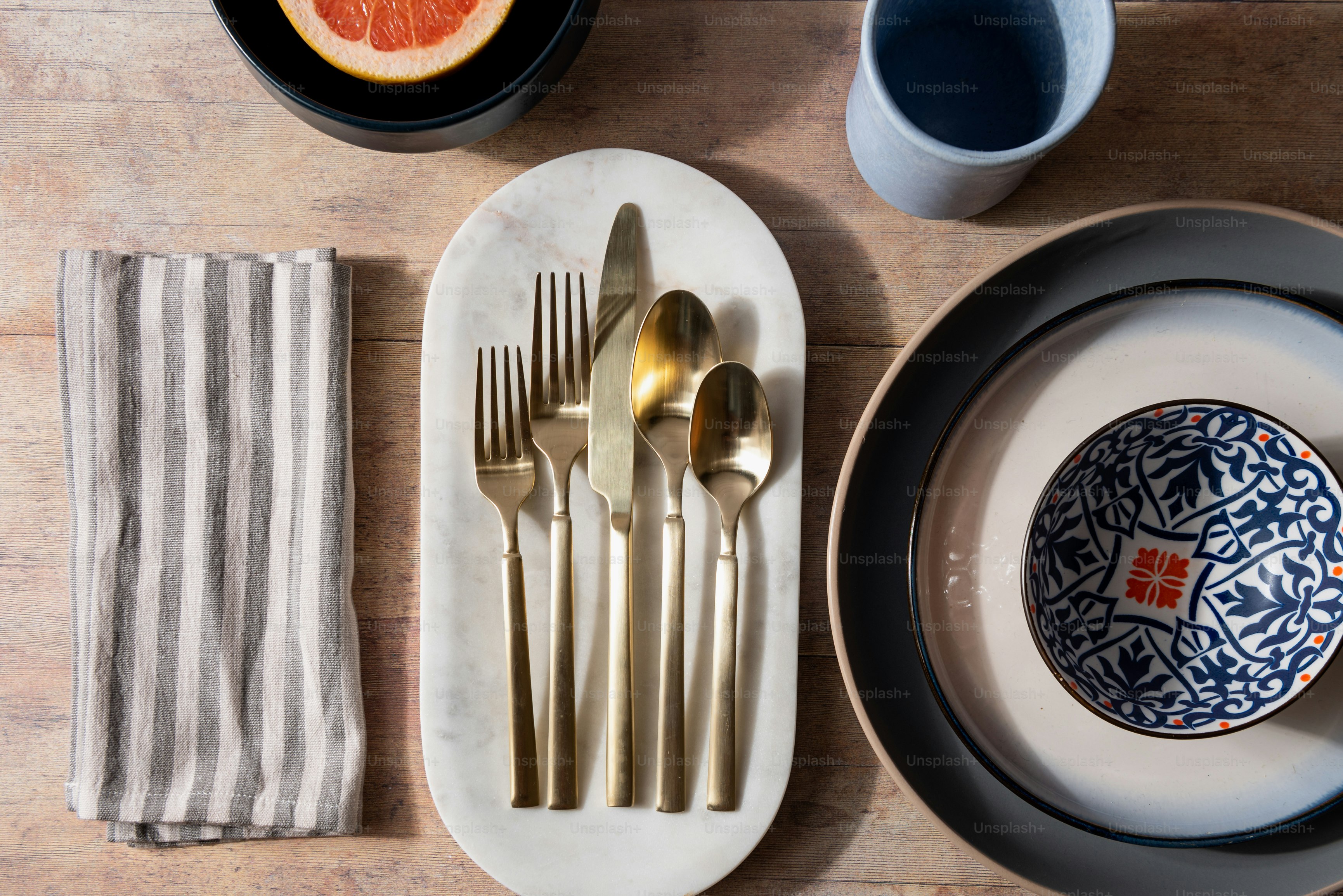 una tavola apparecchiata con un piatto, posate e un pompelmo