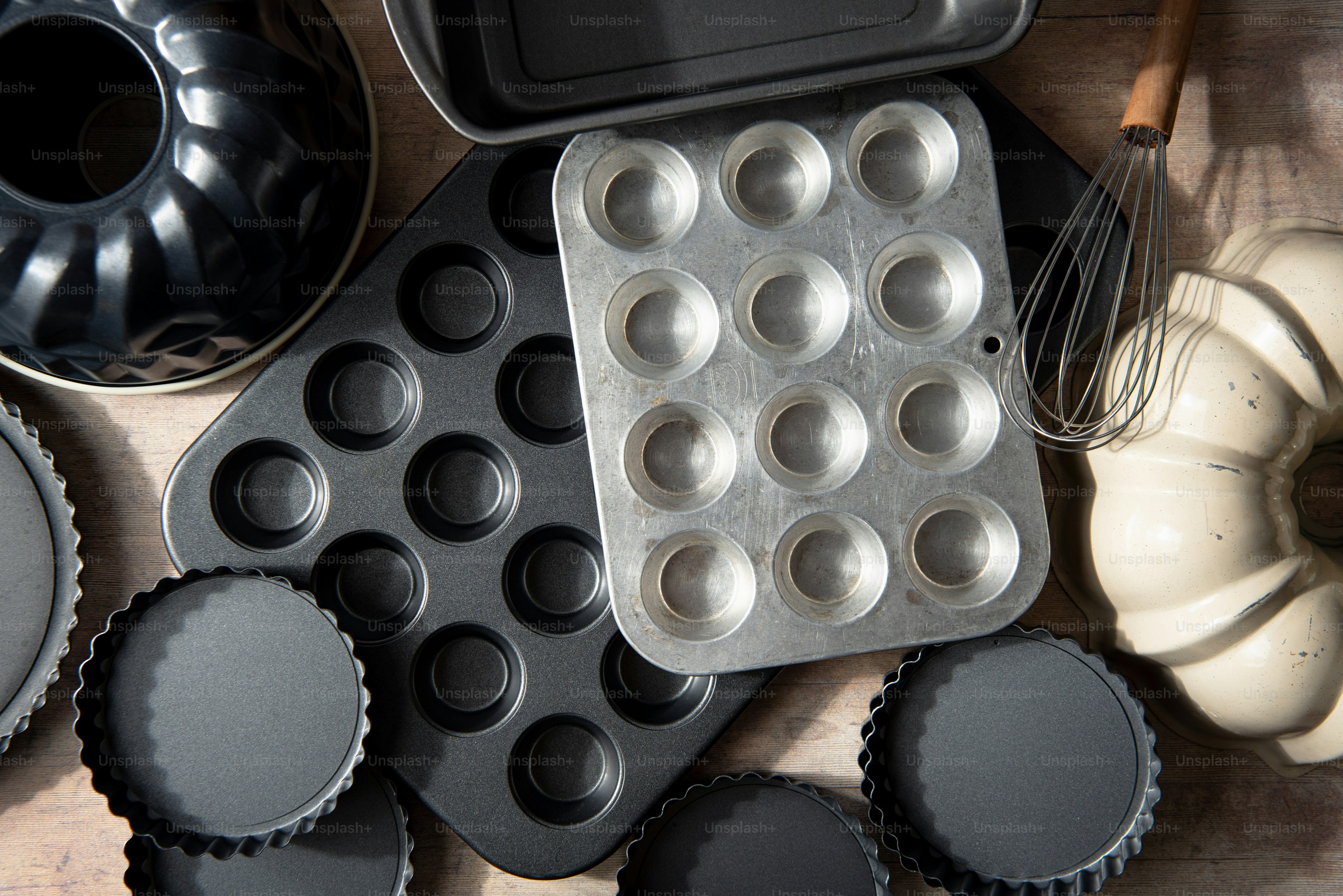 a muffin tin with some cupcakes and a whisk