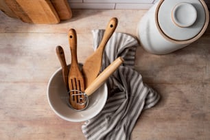 una ciotola bianca piena di utensili di legno e cucchiai di legno