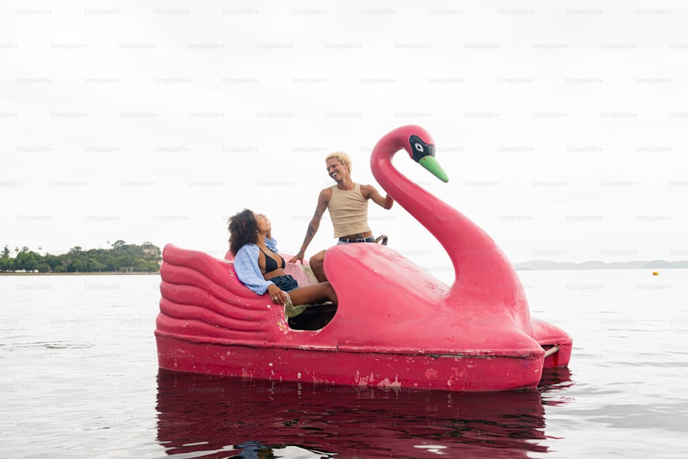 a couple of people riding on a pink boat in the water