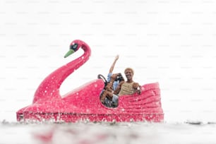 a man and a woman ride a pink swan boat