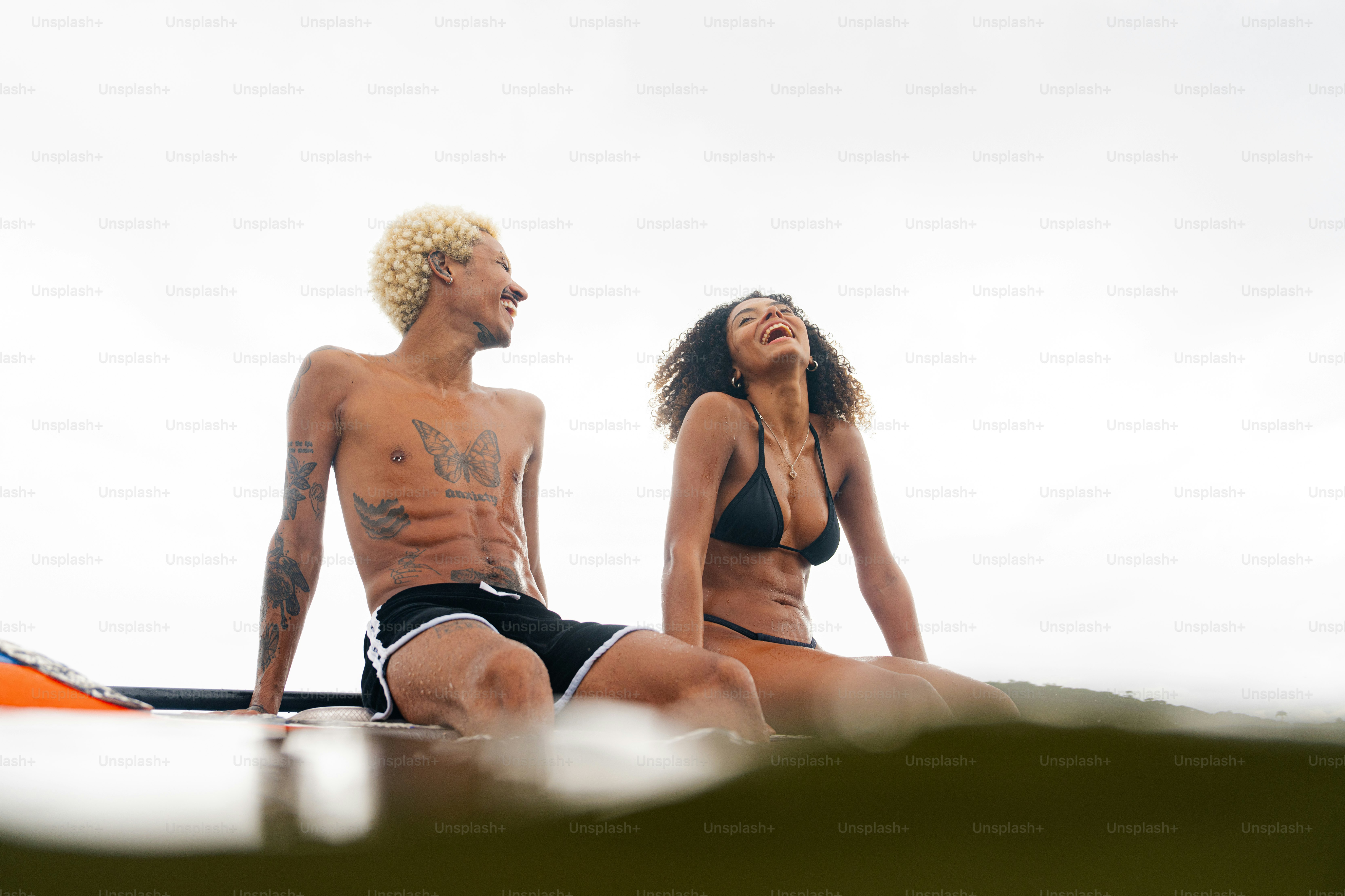 a man and a woman sitting on a surfboard