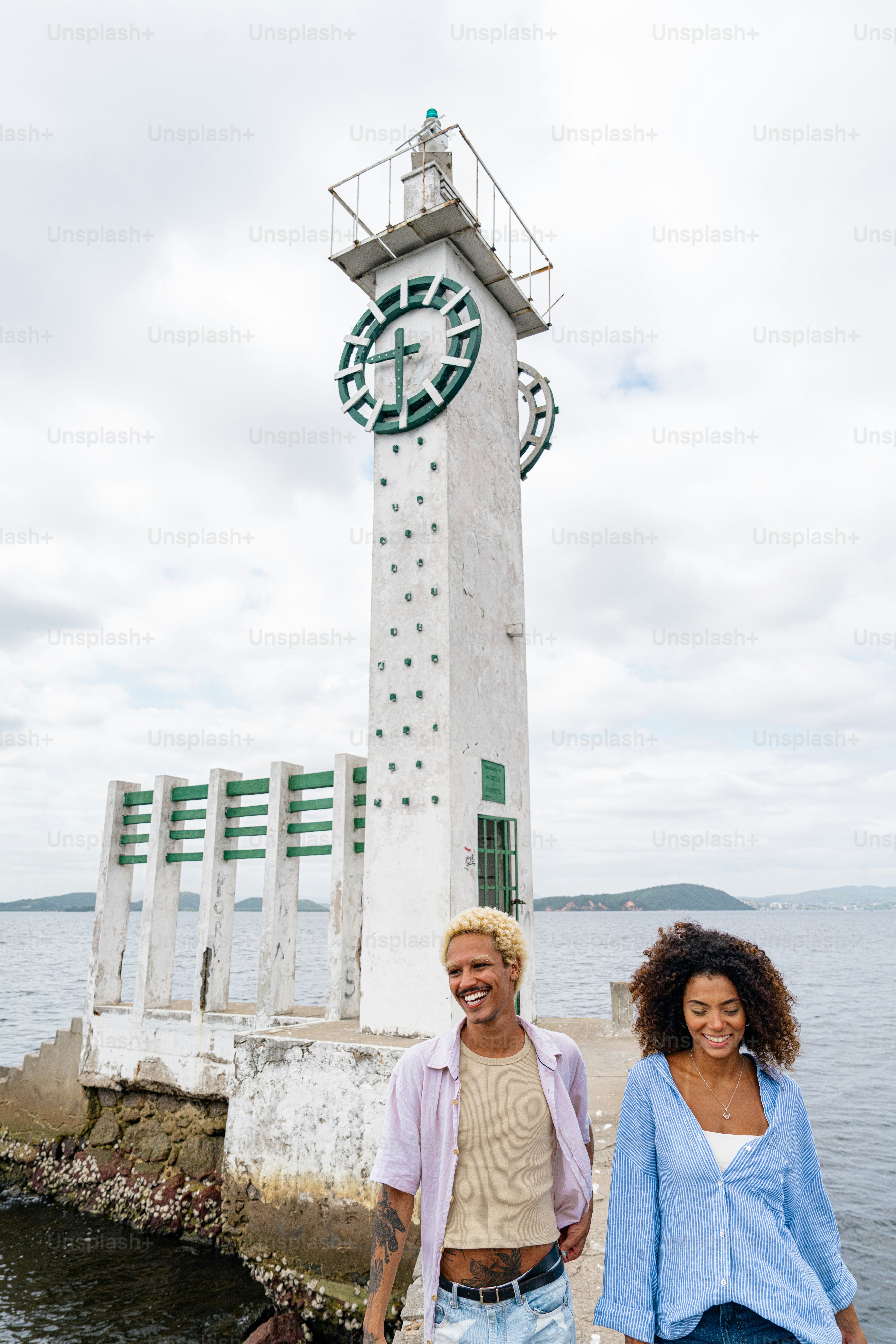 a man and a woman are standing in front of a lighthouse
