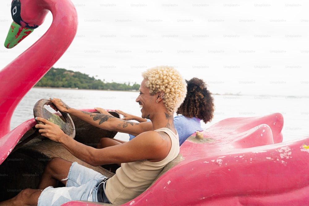 a man driving a pink flamingo boat on a lake