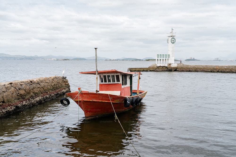 a red and white boat tied up to a dock