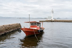 a red and white boat tied up to a dock