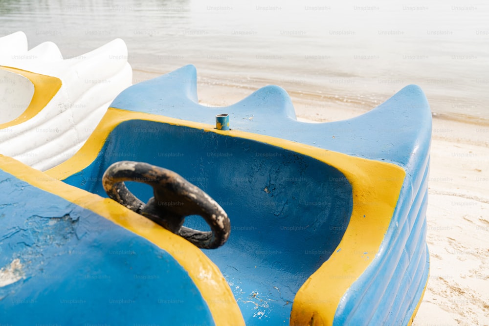 a close up of a blue and yellow boat on a beach