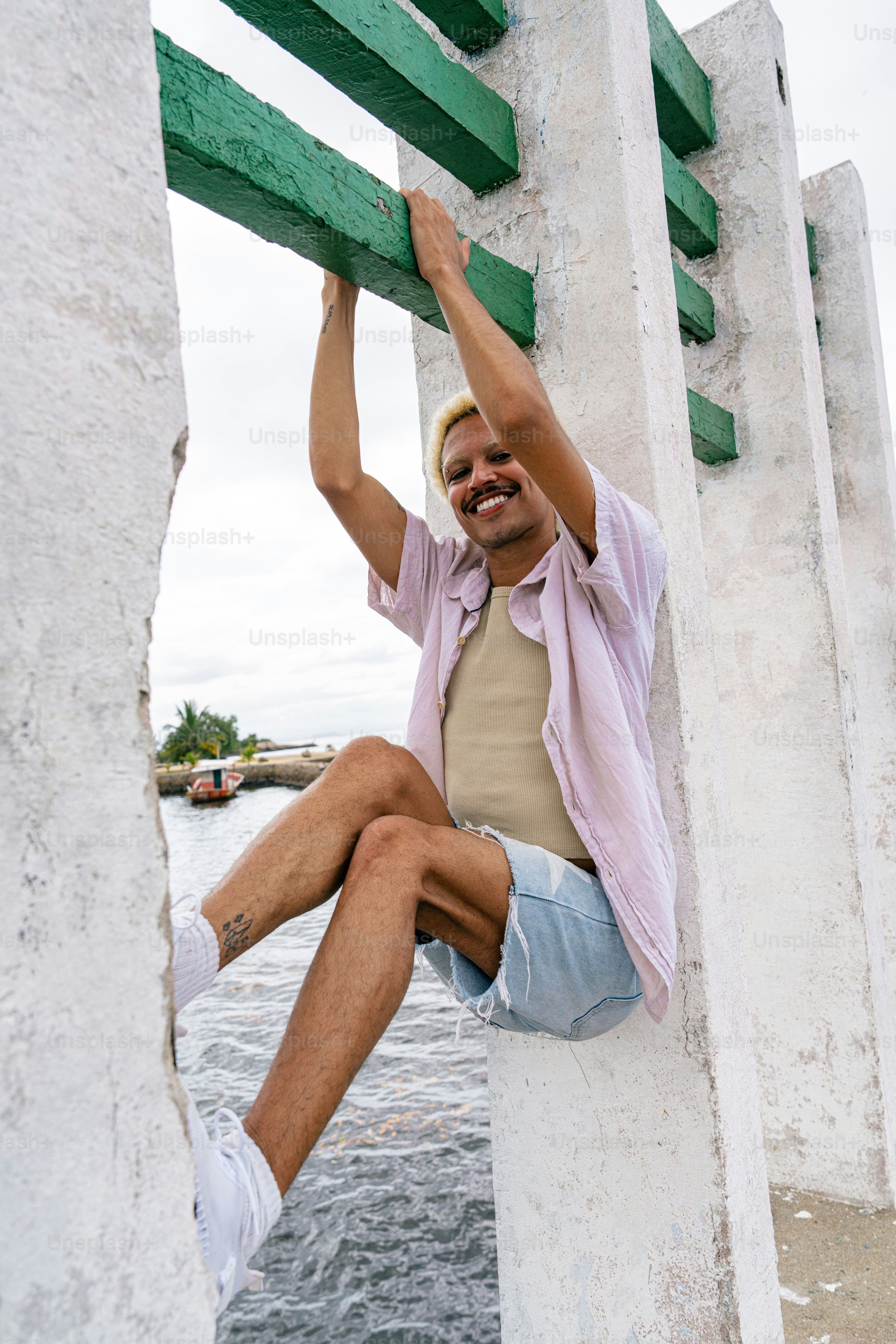 a man sitting on top of a white pillar next to a body of water