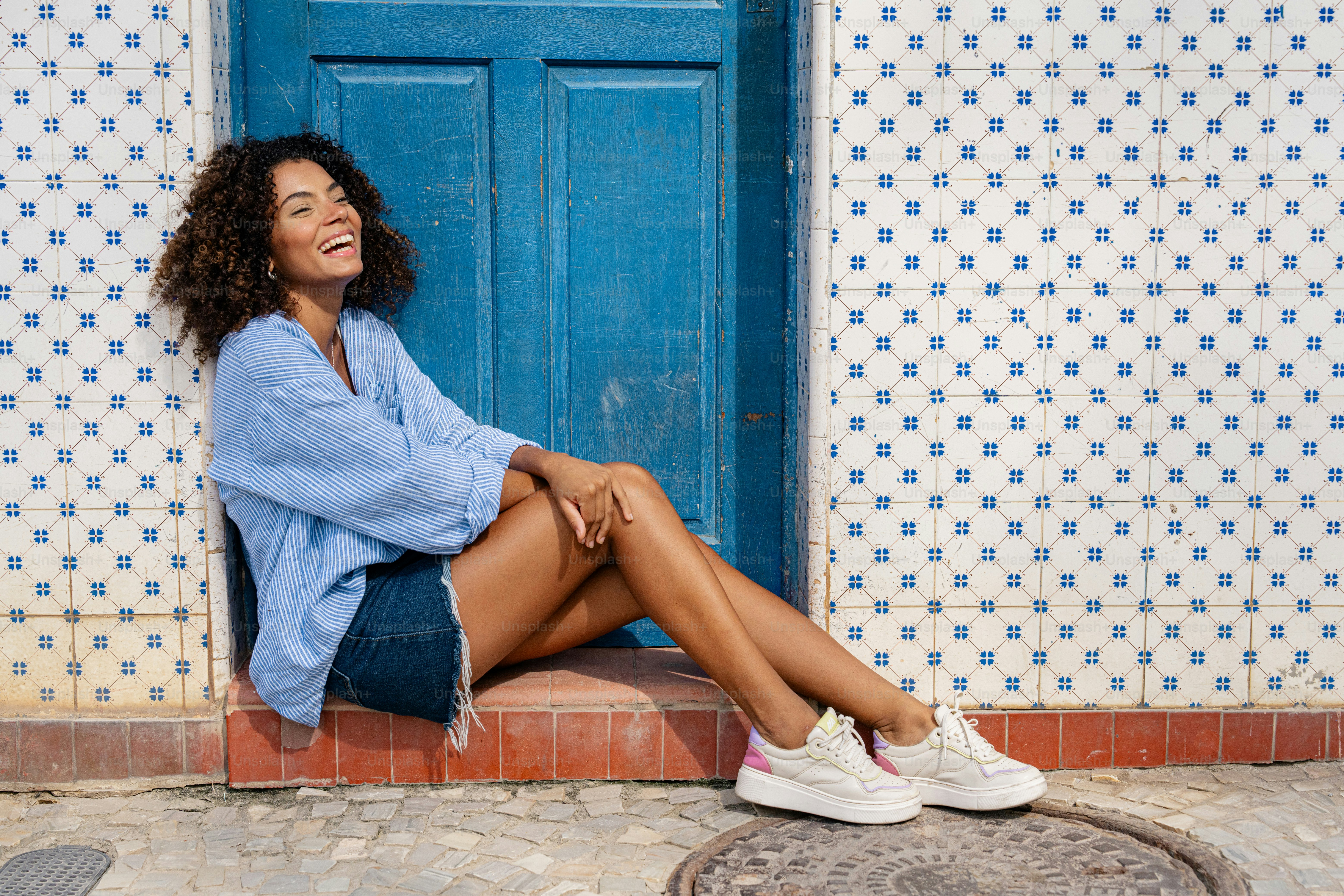 a woman sitting in front of a blue door
