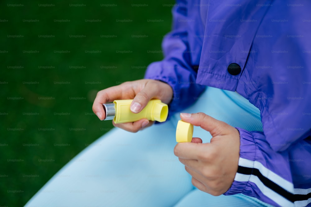uma pessoa sentada em um banco com um objeto amarelo na mão