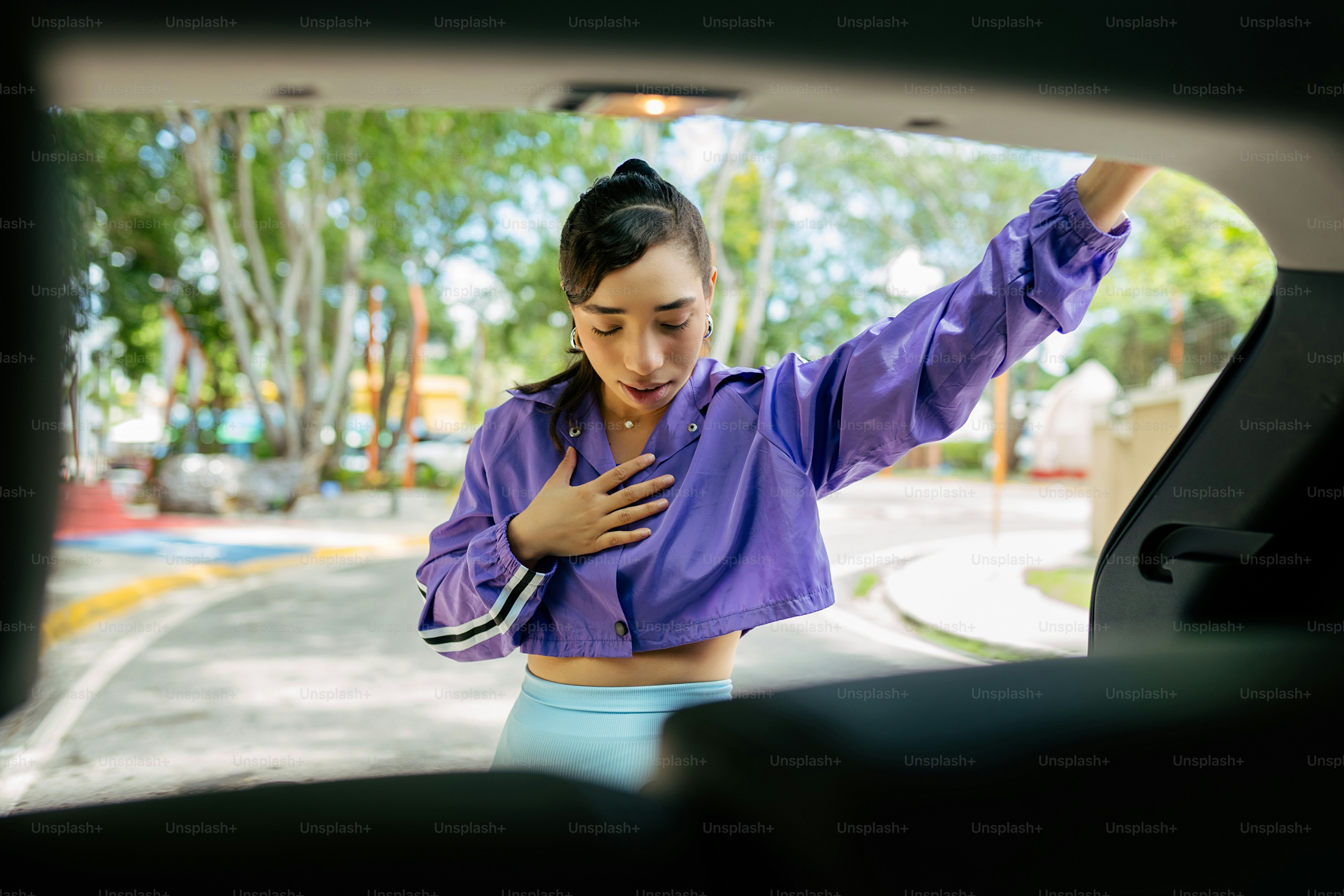 Una donna in una camicia viola sta guardando fuori dal finestrino di un'auto