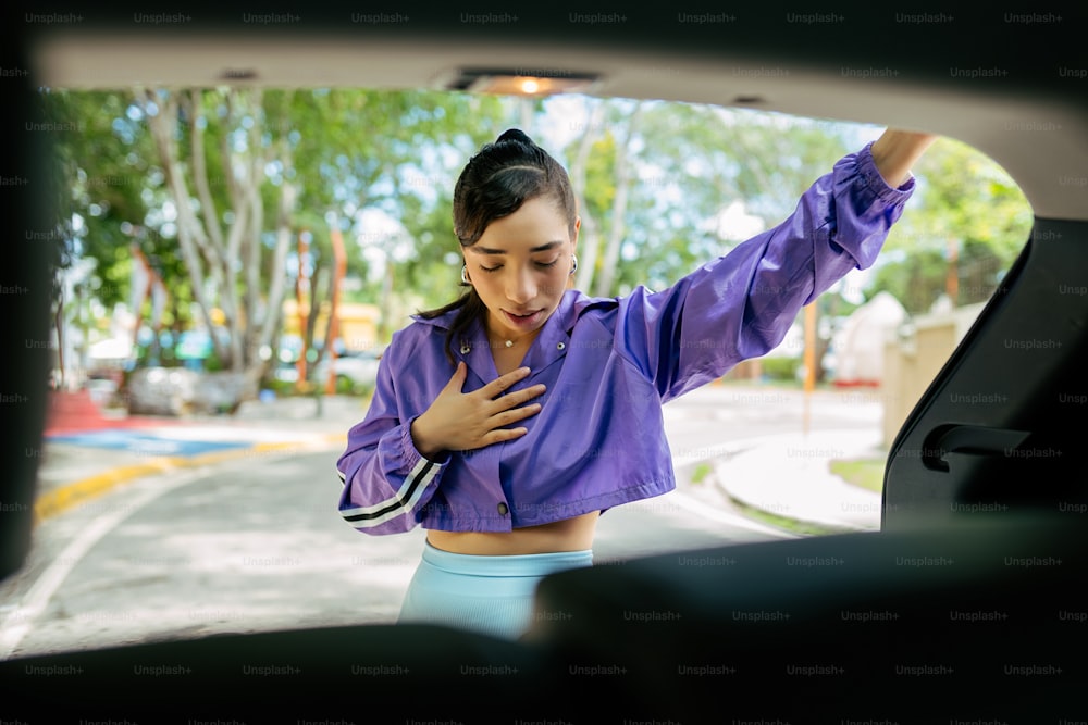 a woman in a purple shirt is looking out the window of a car