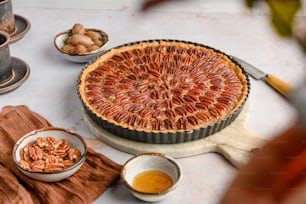 a pie sitting on top of a table next to bowls of nuts