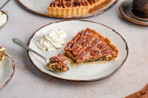 a slice of pecan pie on a plate with whipped cream