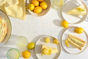una mesa cubierta con platos de pastel y limones