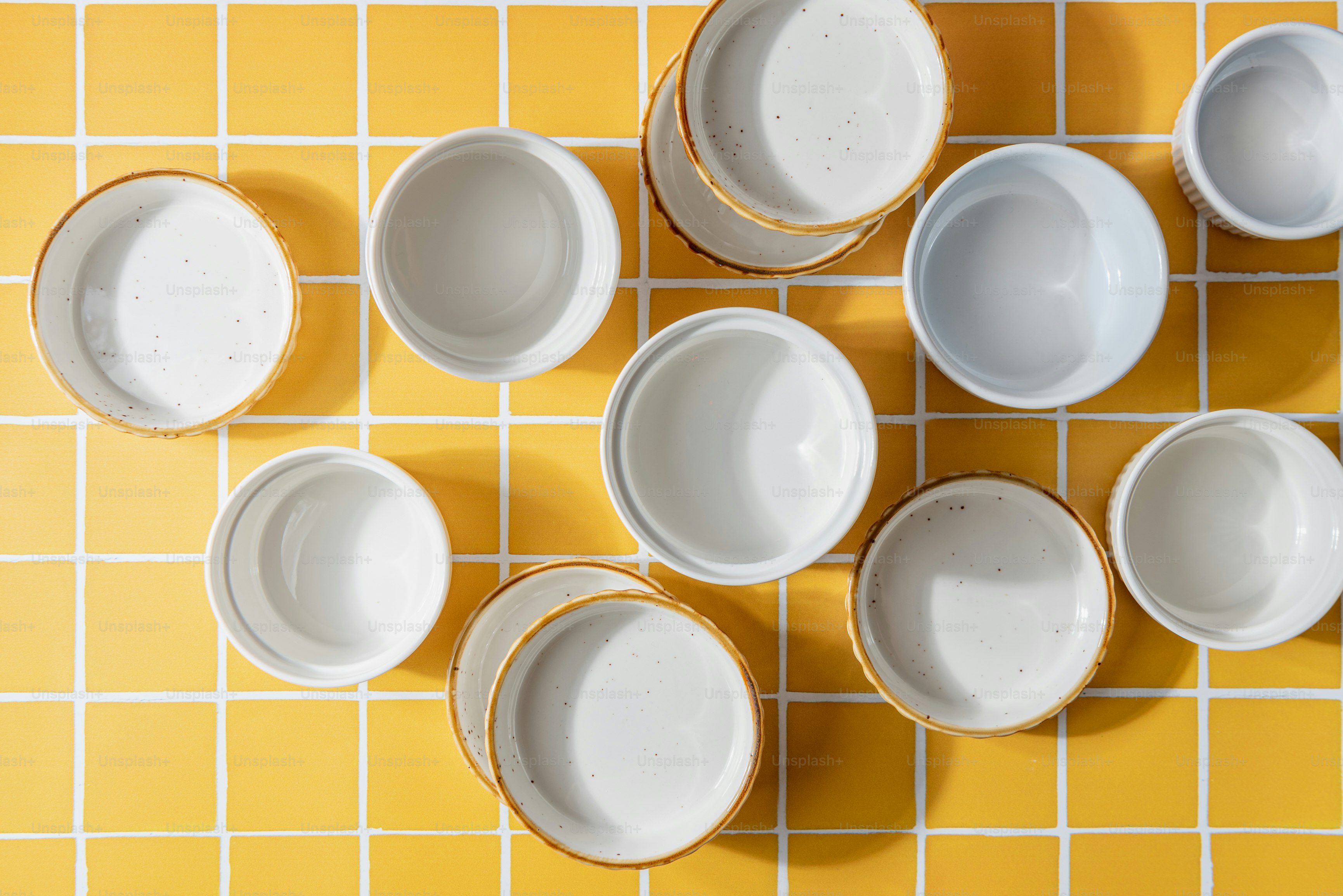 un gruppo di ciotole bianche sedute sopra un pavimento piastrellato giallo