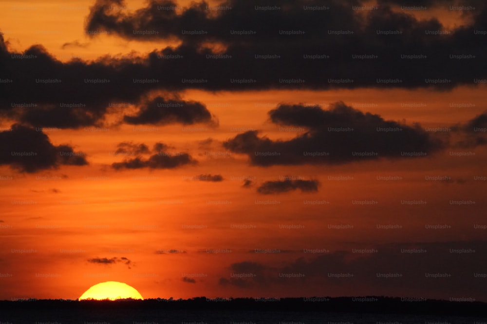 the sun is setting over the horizon of the ocean