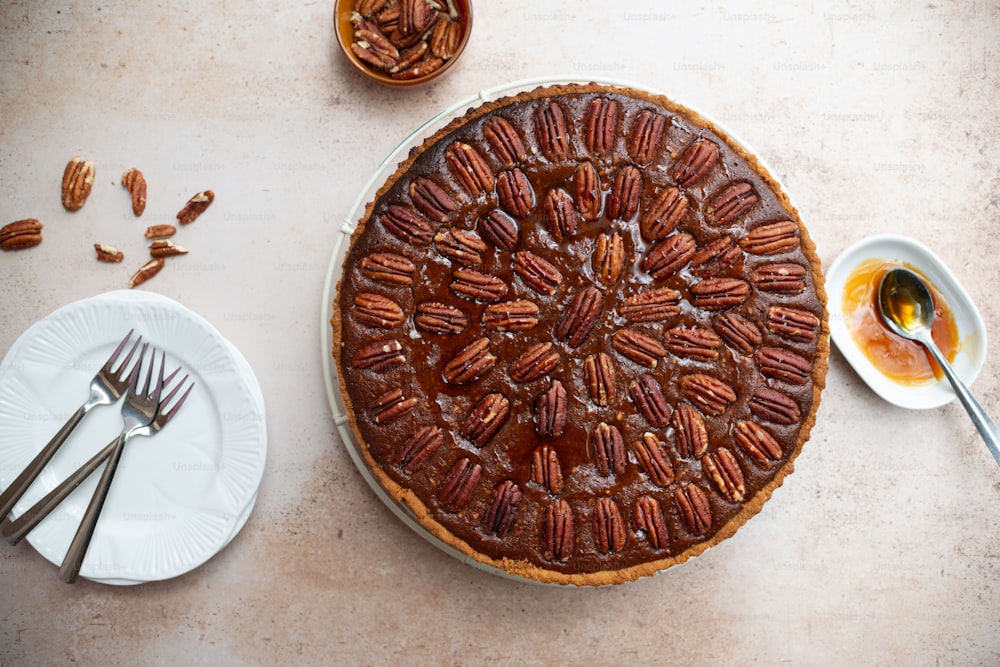 a pecan pie on a table with a fork and a plate of pecans