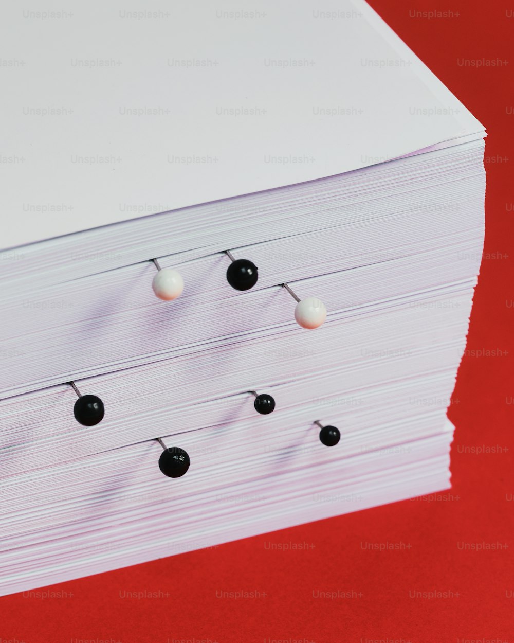 a bunch of small black and white balls on a red surface