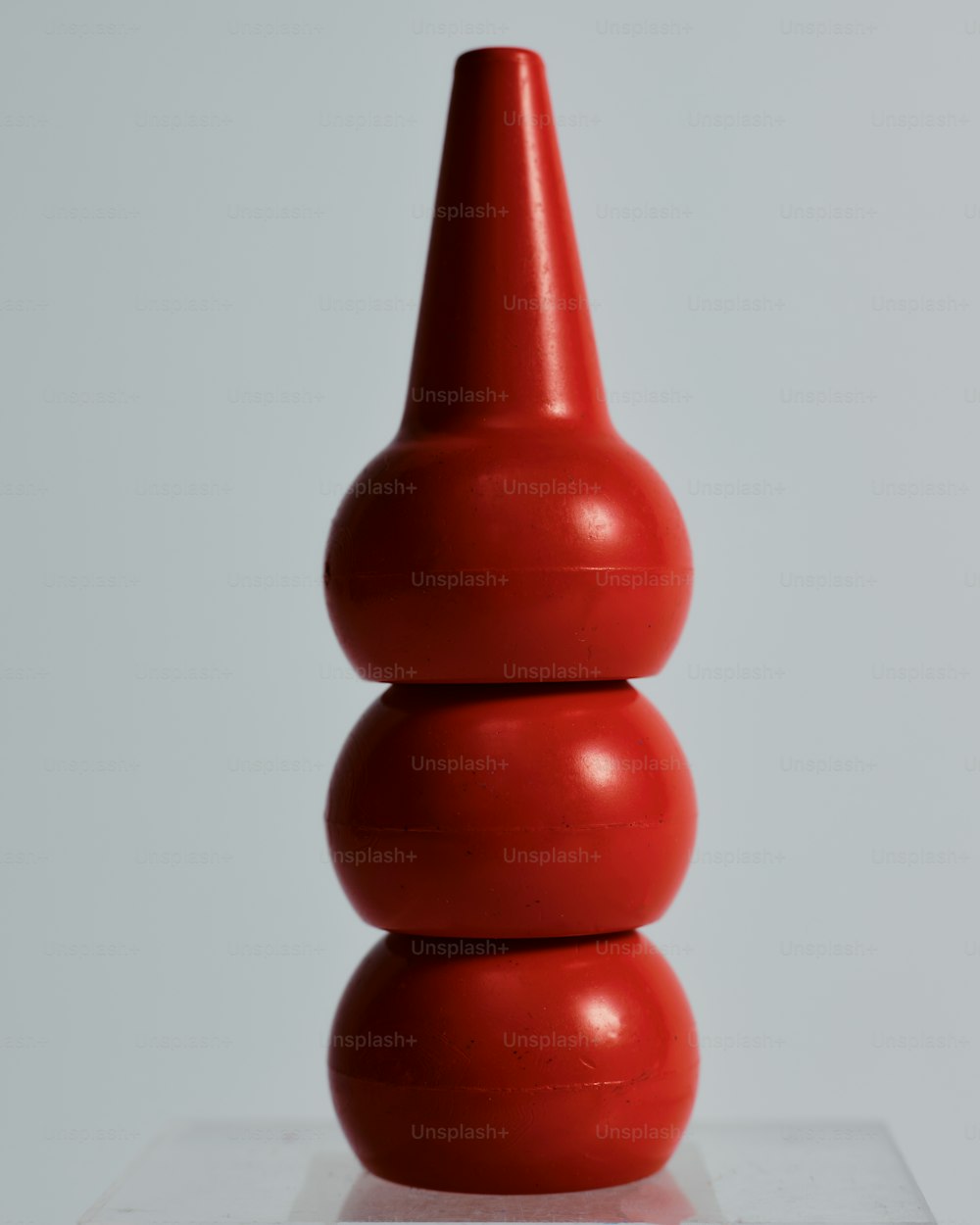 a red vase sitting on top of a white table