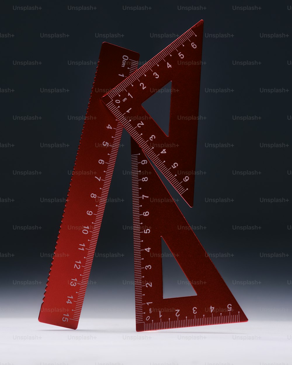 a red plastic ruler with a triangle on top of it