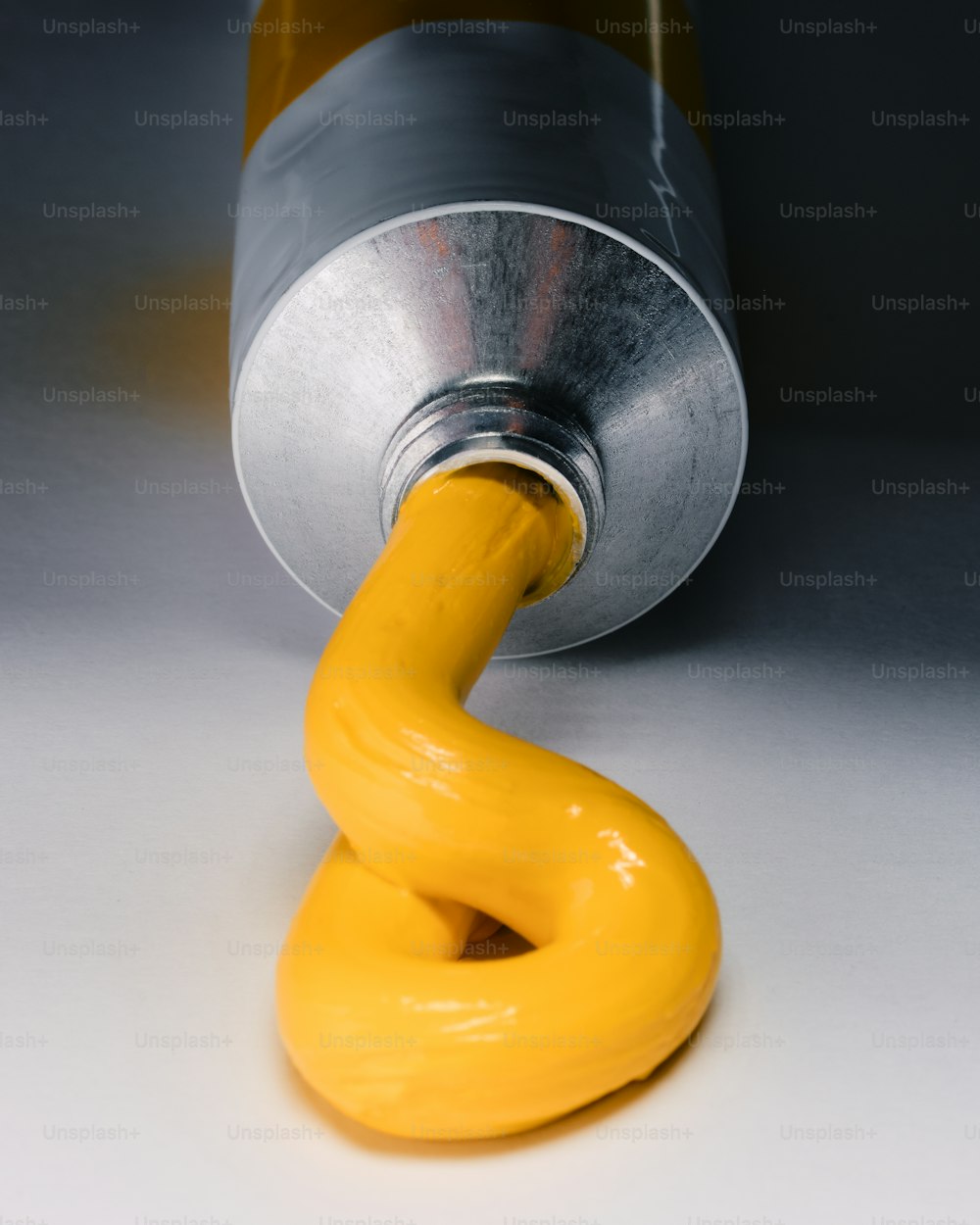 una lata de metal con un mango amarillo sobre una superficie blanca