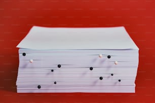 a stack of white papers sitting on top of a red table