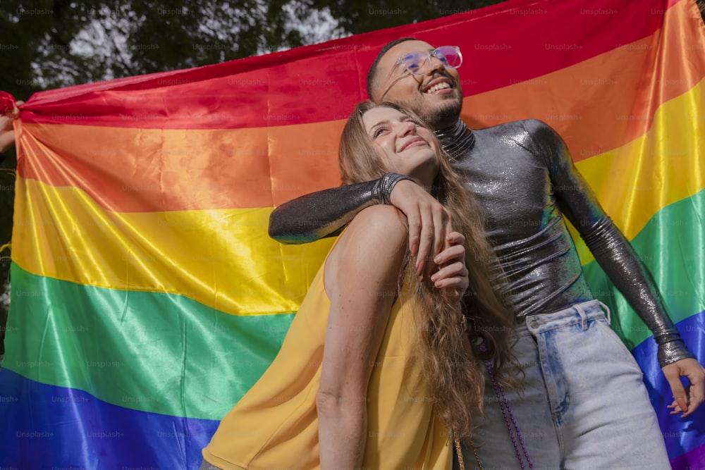 a man and a woman standing in front of a rainbow flag