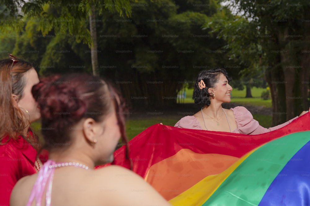 a group of women standing around each other holding a rainbow flag