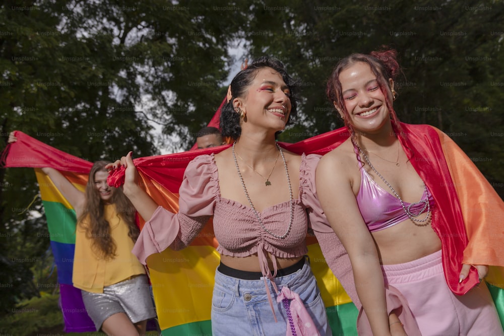 two women in bikinis are holding a rainbow flag