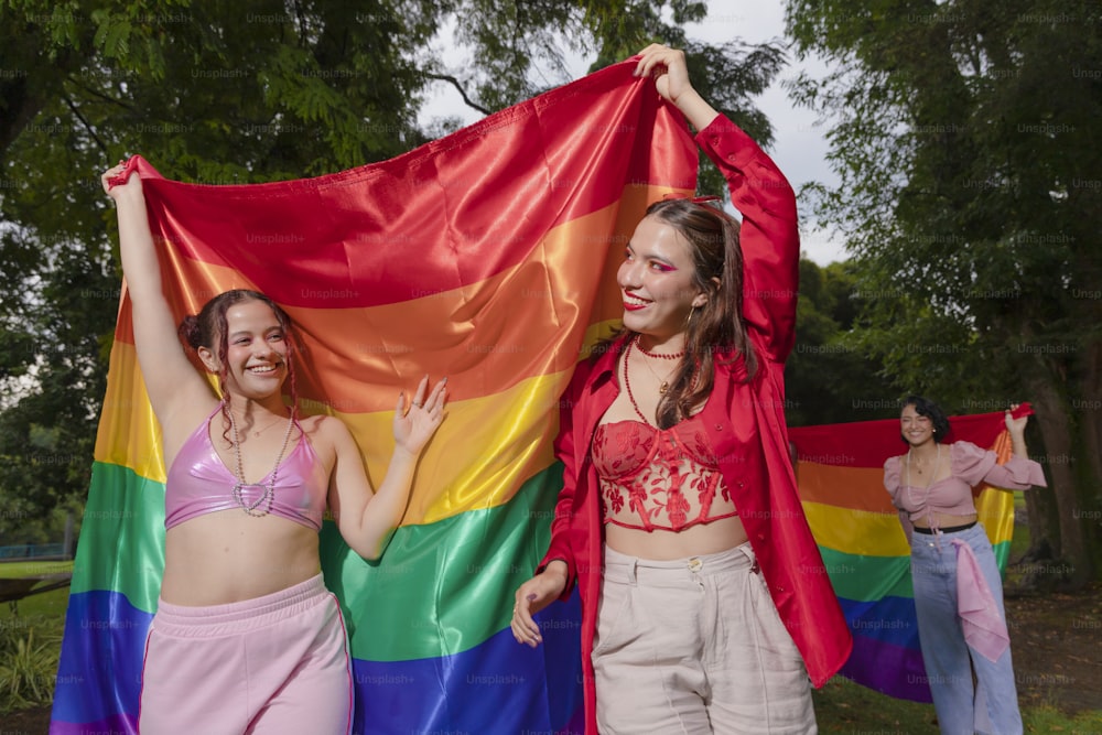 two women holding a rainbow flag in a park