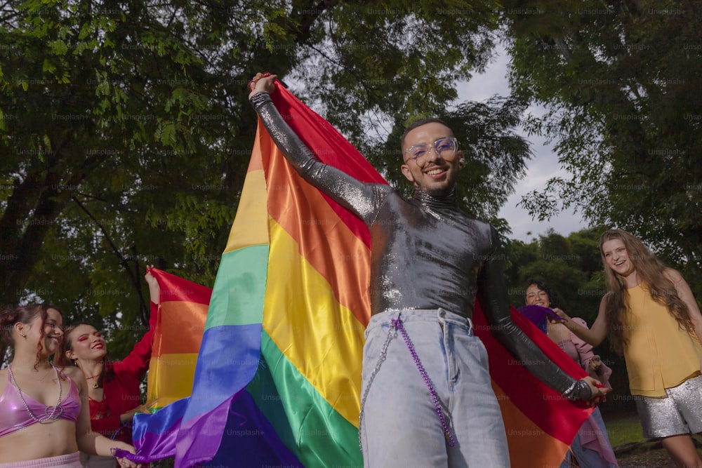 a man holding a rainbow flag in front of a group of girls