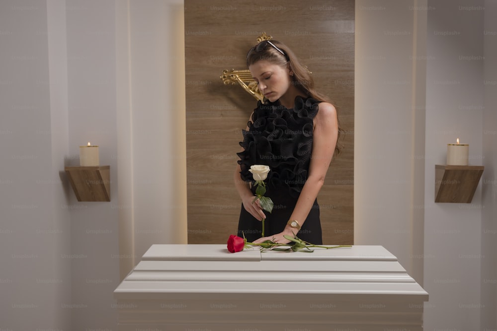 a woman standing in front of a table with a rose on it