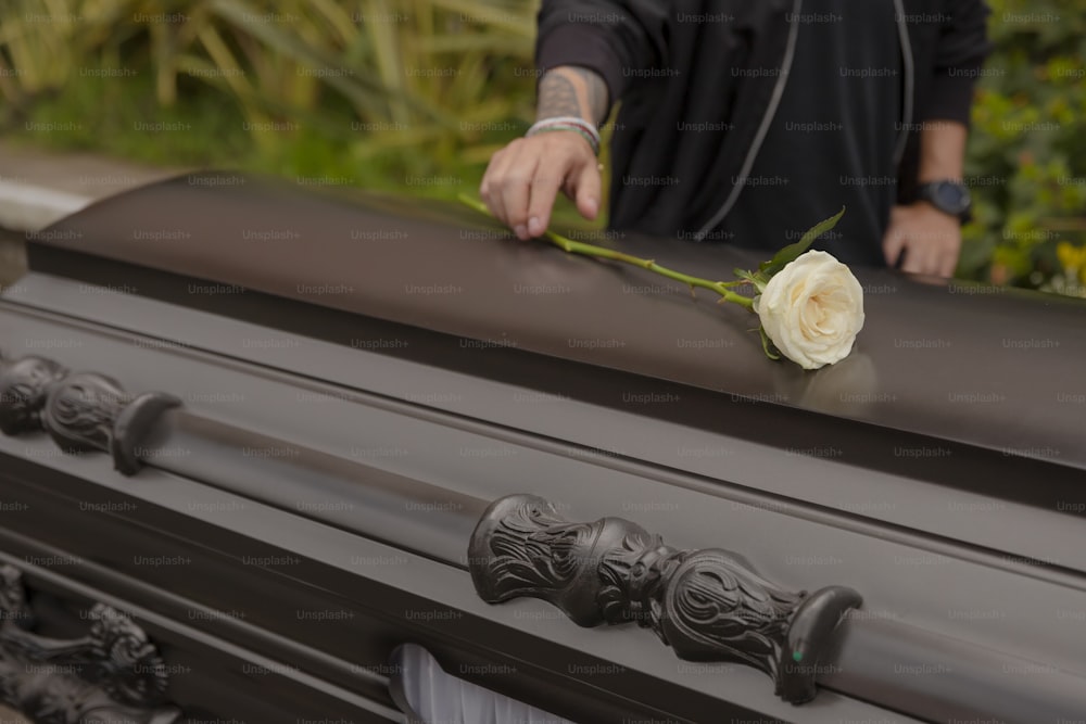 a person placing a rose on top of a casket