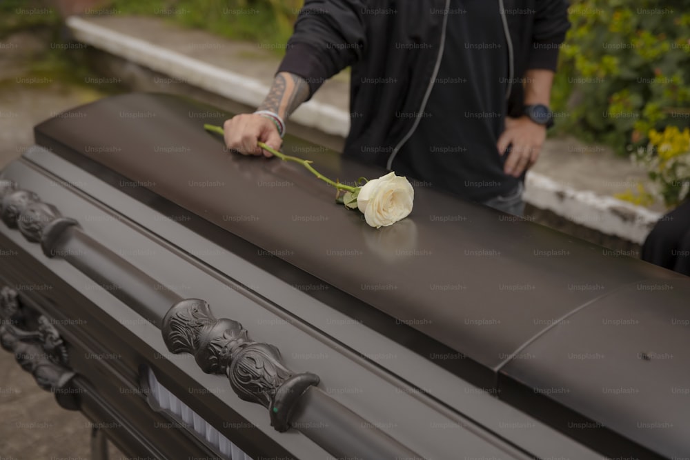 a man holding a flower on top of a black roof