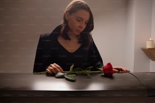 a woman sitting at a table with a rose