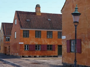 an orange building with red shutters next to a street light