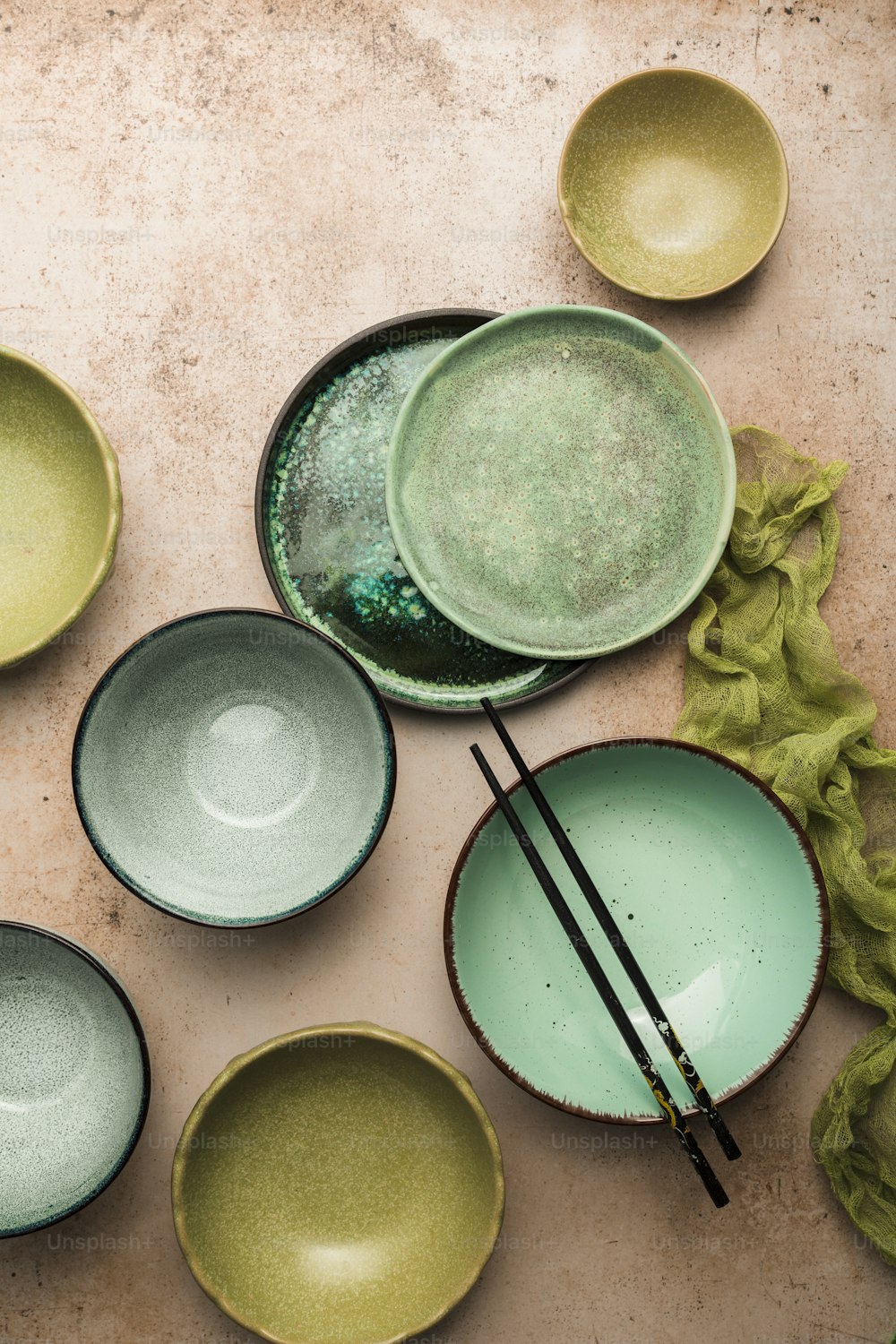 a table topped with green plates and chopsticks