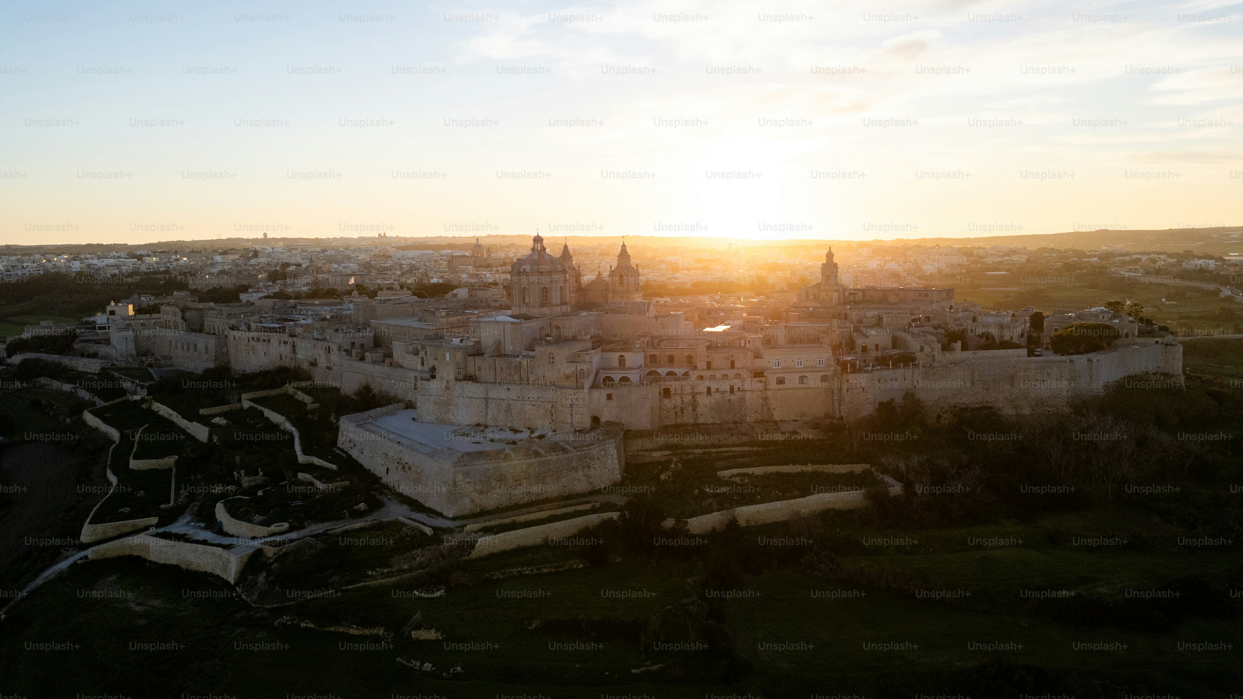 an aerial view of a castle with a sunset in the background