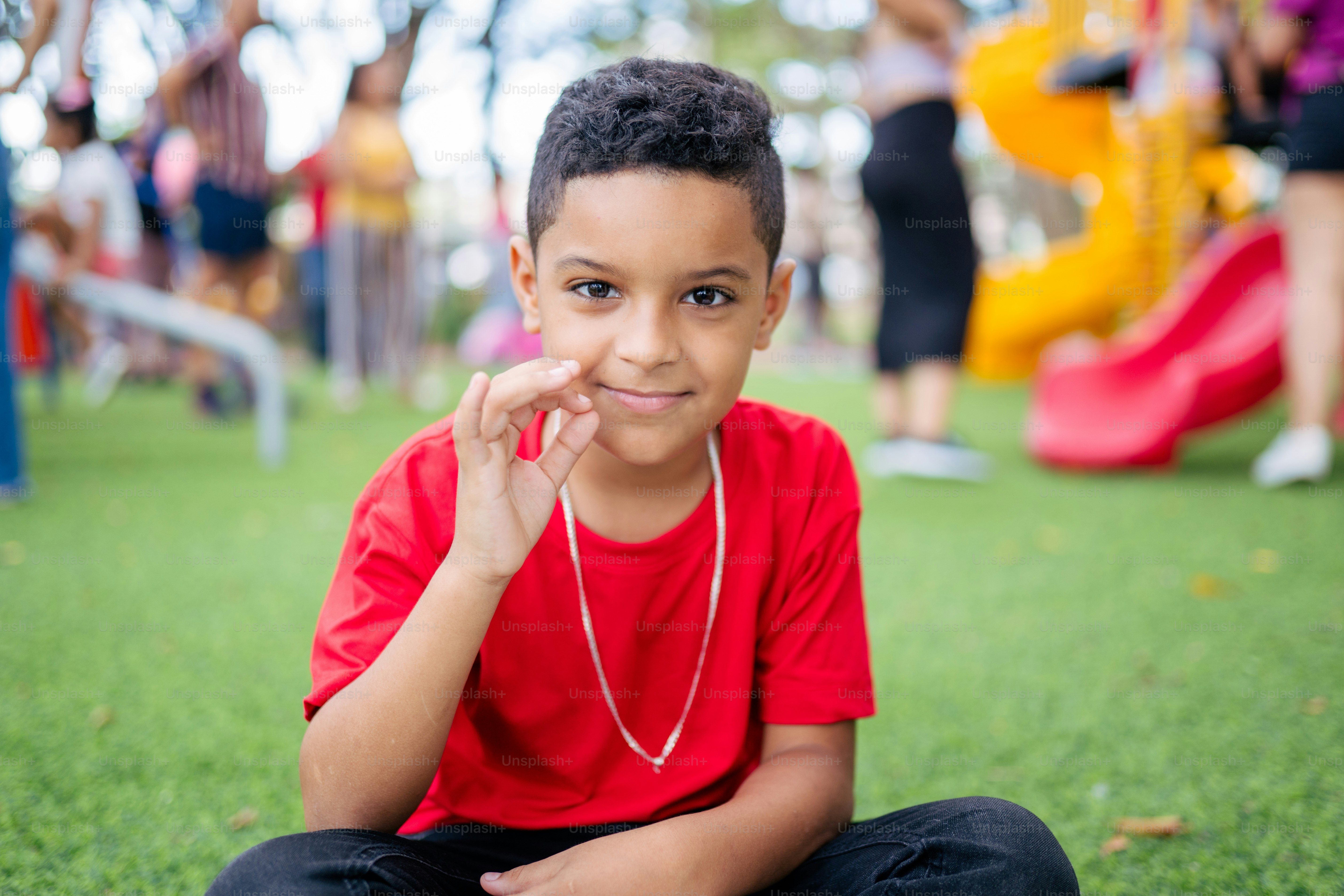 a young boy sitting on the ground in a park