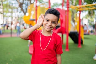 a young boy in a red shirt standing in front of a playground