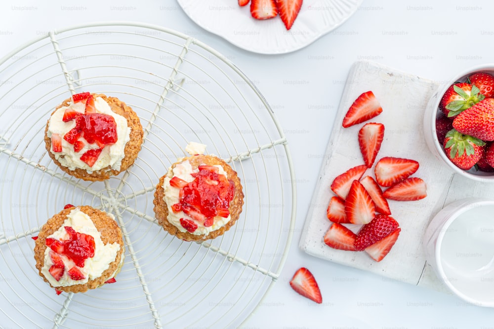 a plate of strawberries and cupcakes on a cooling rack
