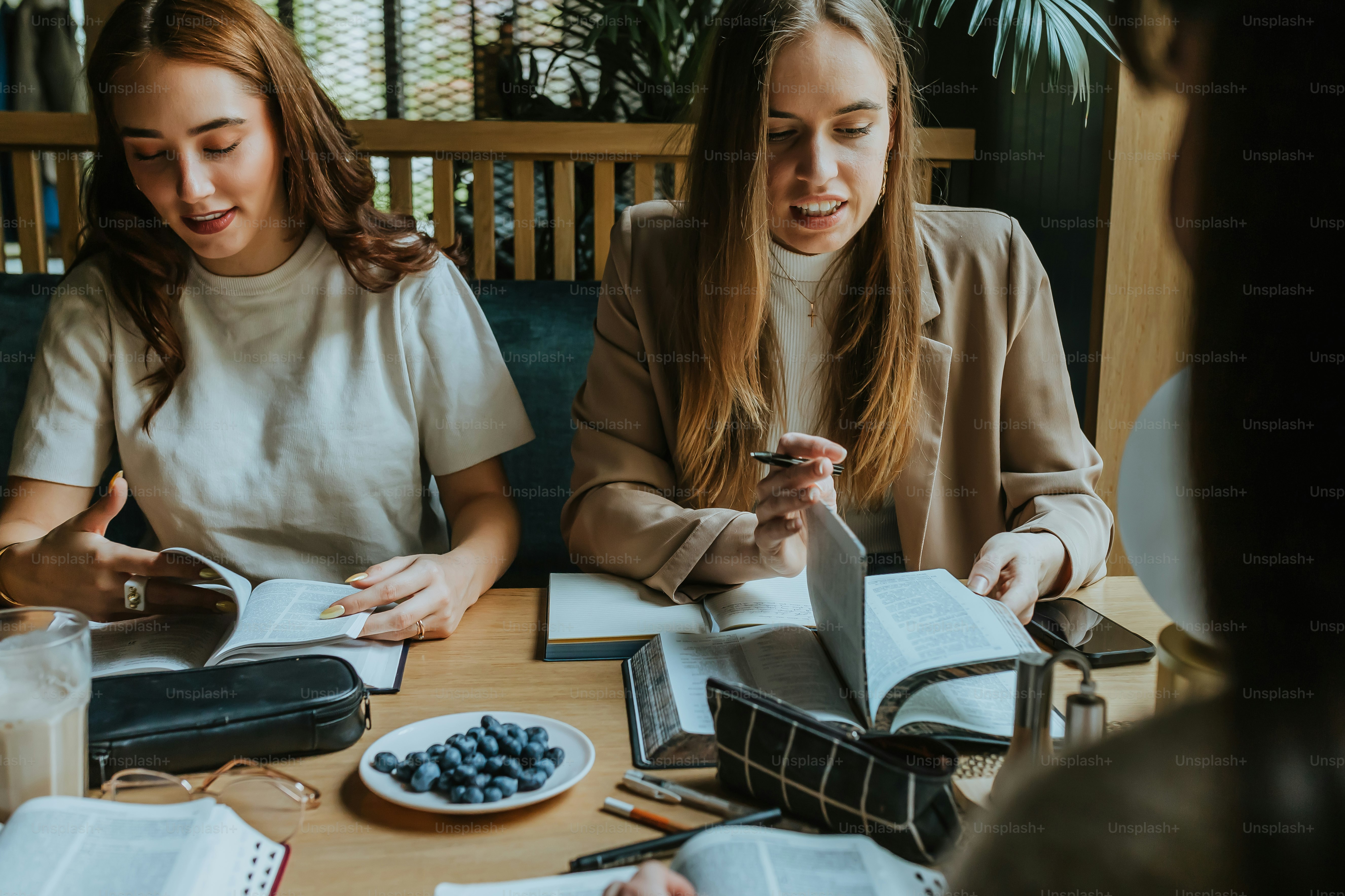 duas mulheres sentadas em uma mesa com livros e cadernos
