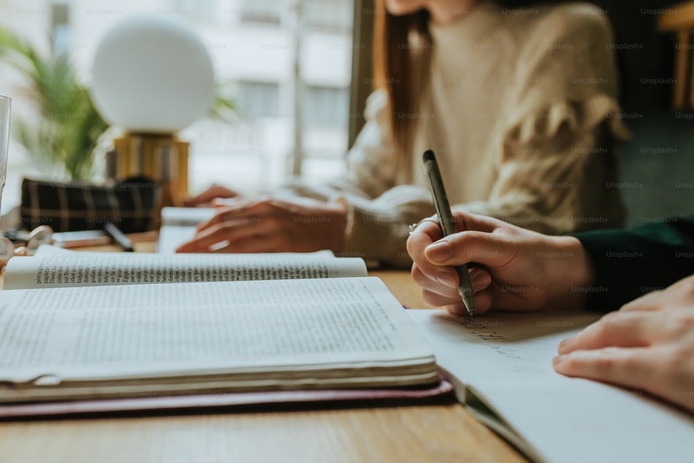 two people sitting at a table with notebooks and a pen