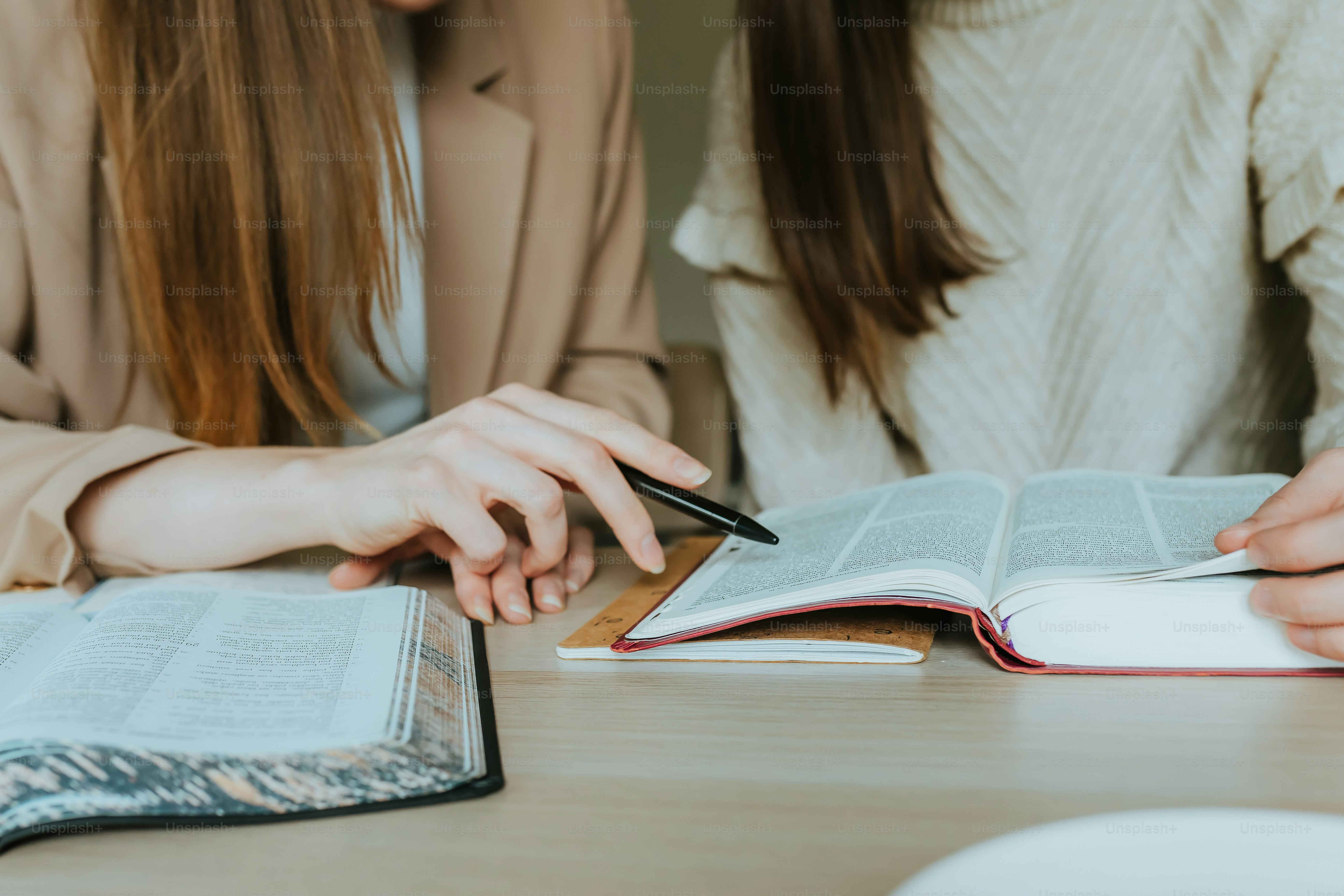 deux femmes assises à une table avec un livre ouvert