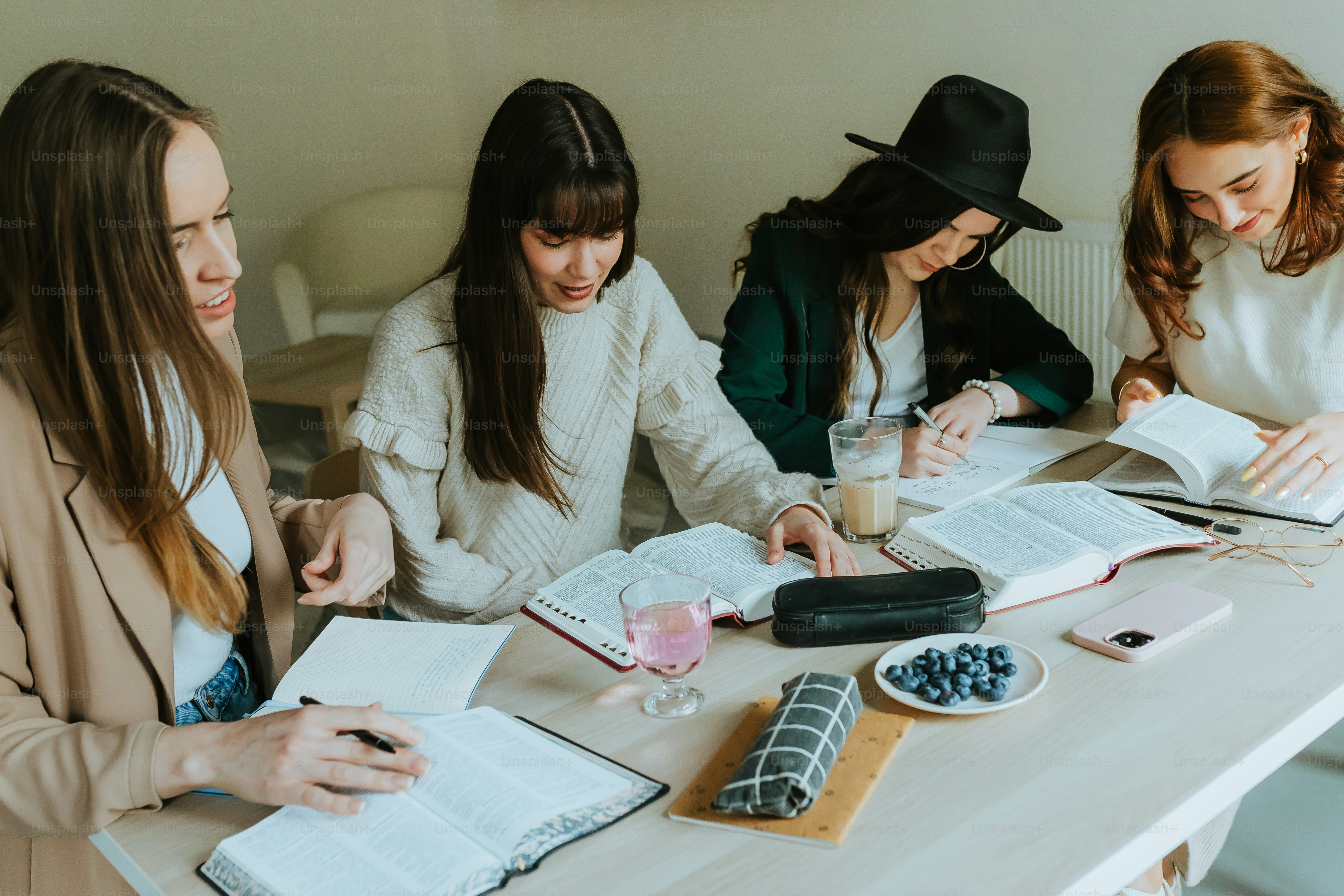 eine Gruppe von Frauen, die mit Büchern um einen Tisch sitzen
