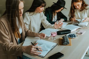 um grupo de mulheres sentadas em uma mesa com cadernos