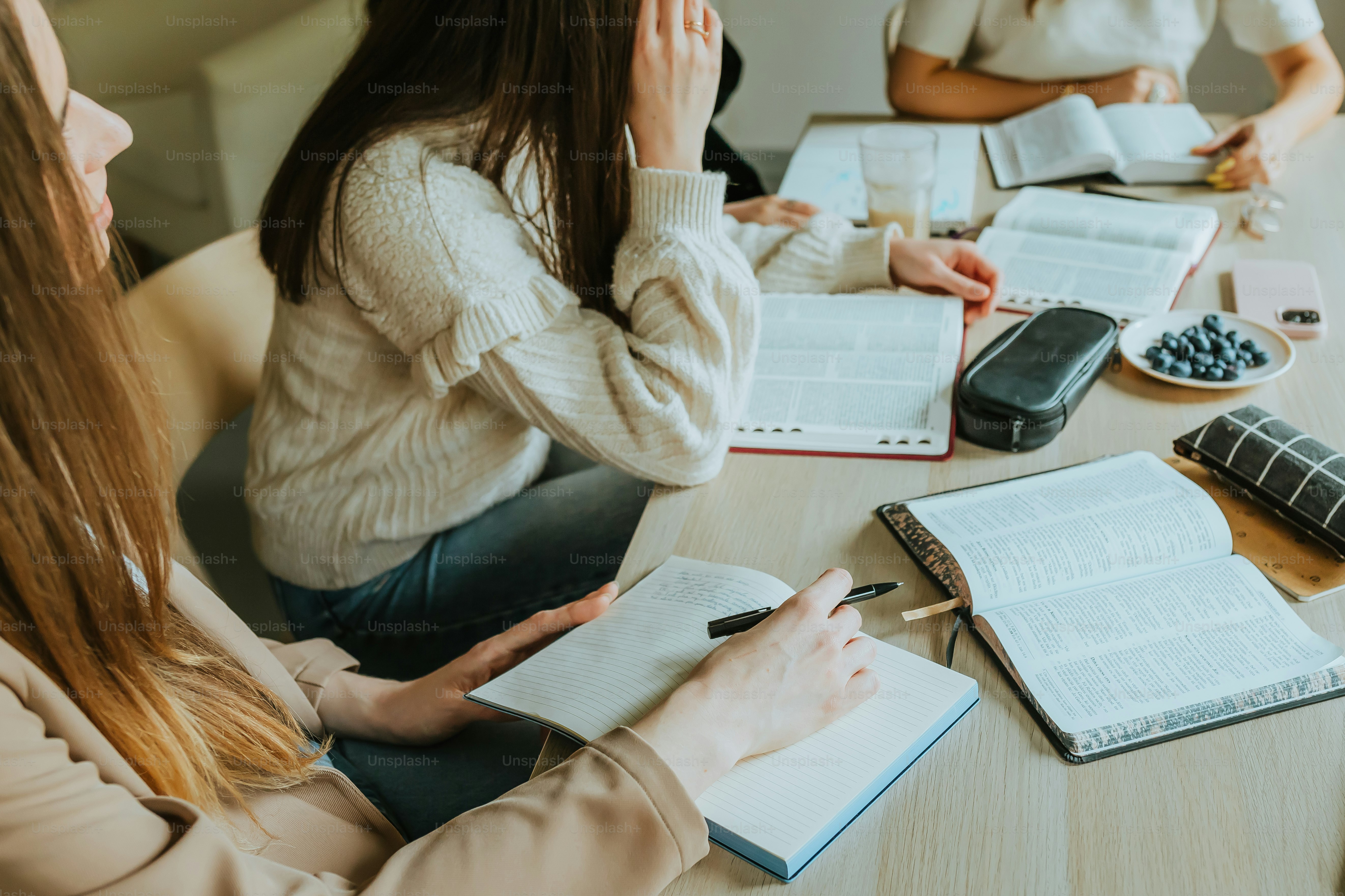 um grupo de pessoas sentadas ao redor de uma mesa com cadernos