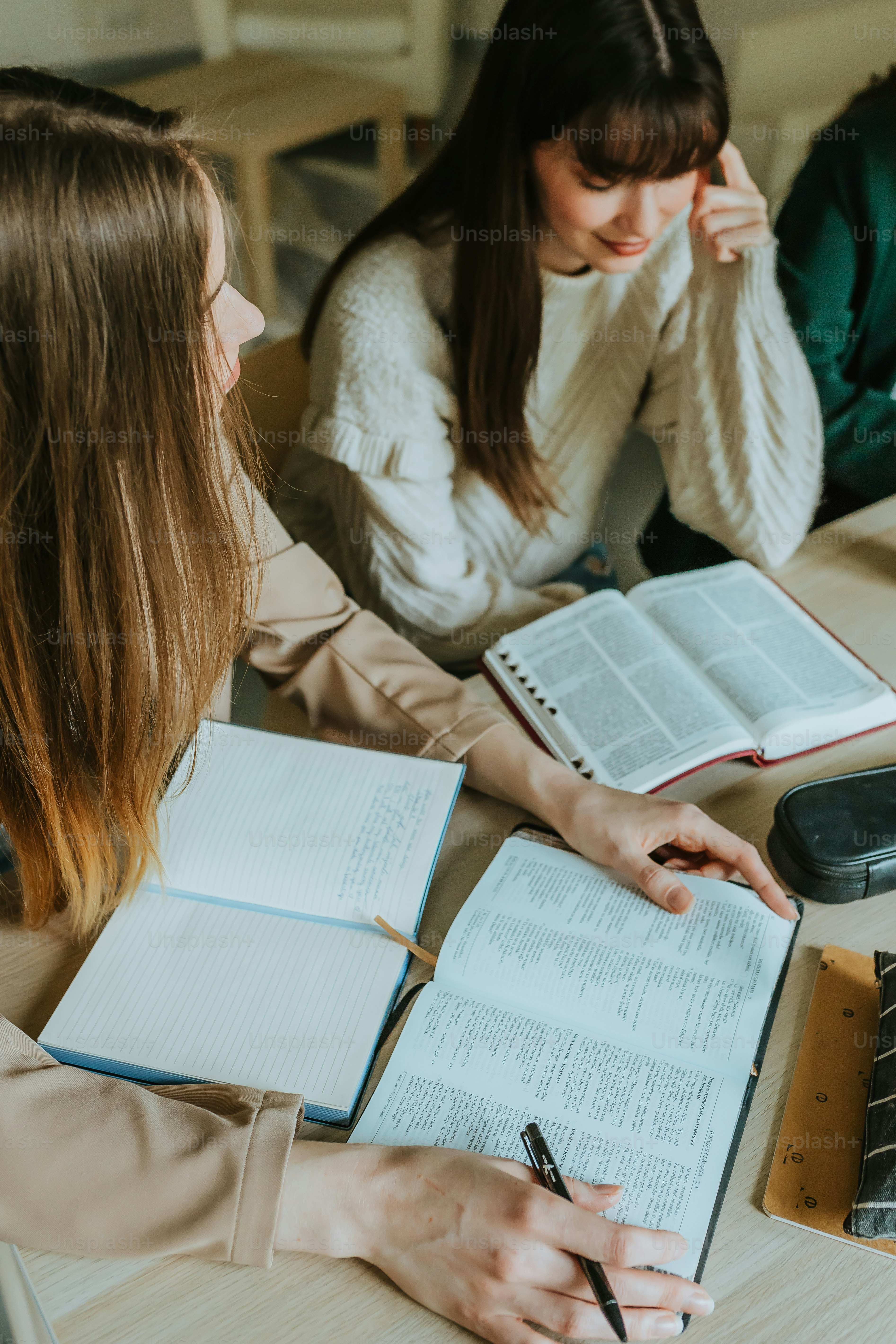 Zwei Frauen sitzen an einem Tisch mit aufgeschlagenen Büchern