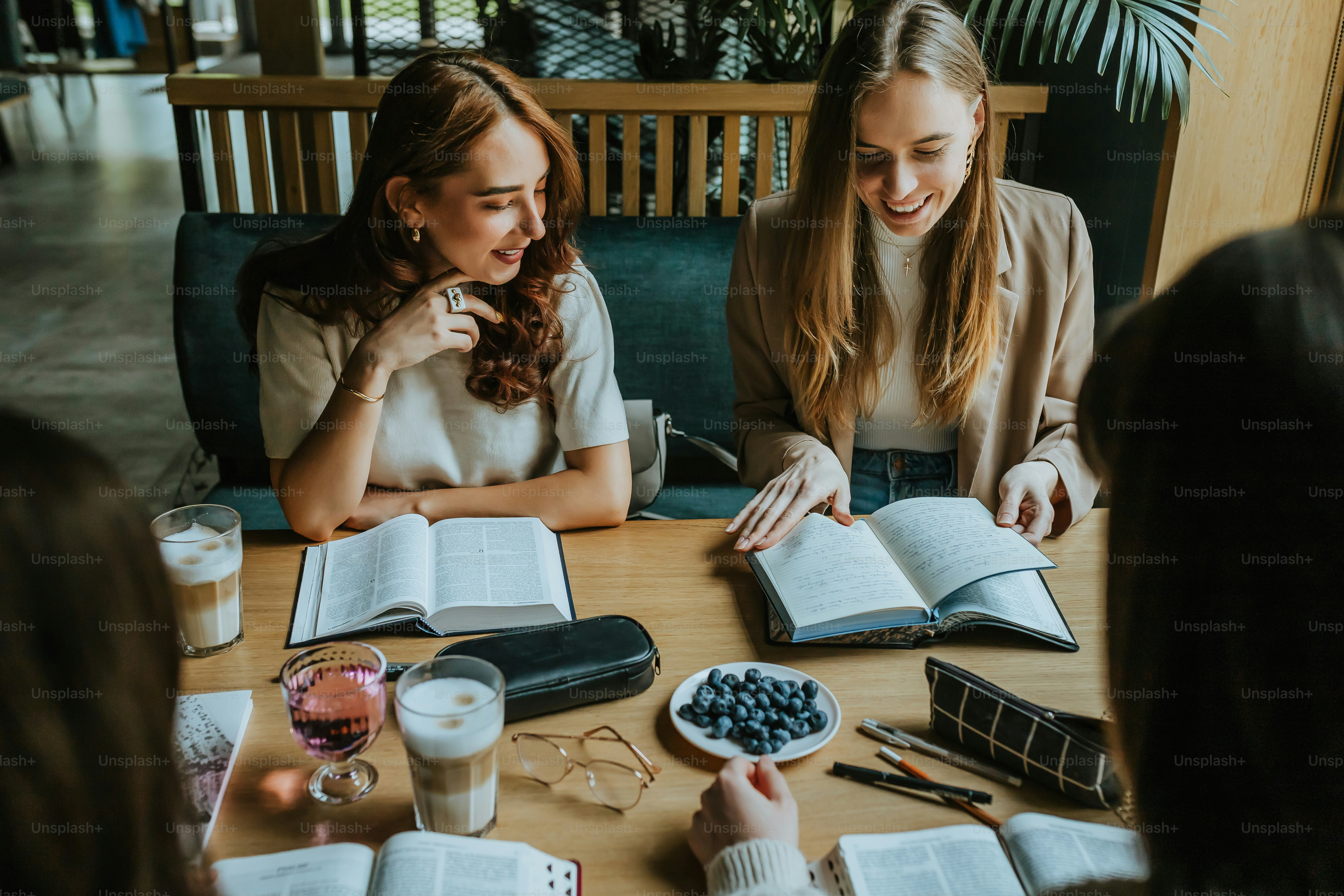 Zwei Frauen sitzen an einem Tisch mit aufgeschlagenen Büchern